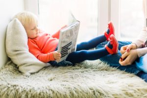 Moving with kids toddler reading a book with caregiver when moved into a new home