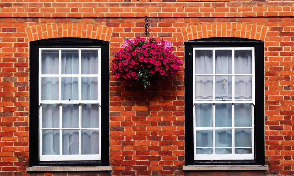 Don't Underestimate Your Exterior: Simple Ways To Add Serious Curb Appeal #CurbAppeal #FrontExterior #HomeImprovements #Hampers&Hiccups Serious Curb Appeal front exterior of brick home with windows hanging pink flowers plant