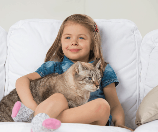 Easy-To-Clean Furniture For Spotless Moms: Leather Furniture, Vinyl Furniture, Fabric Furniture, Bean Bag Chairs are all easy to clean pieces of furniture. #Cleaning #HomeDecor #Furniture #Hampers&Hiccups Easy-to-clean furniture girl holding cat on white fabric couch