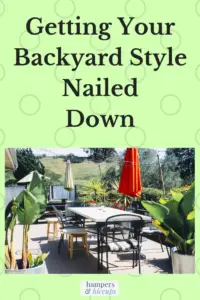 Branching Out? Getting Your Backyard Style Nailed Down backyard patio with table chairs umbrellas large plants privacy fence hamperandhiccups