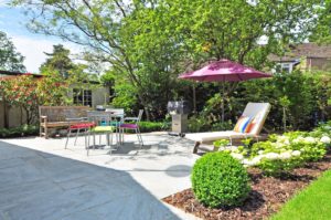 Backyard space with a patio louge chair with umbrella deck chairs bench landscaping