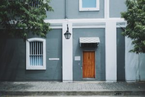Home Exteriors wooden front door white barred windows sidewalk cobalt blue exterior paint
