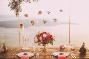 Flower wedding decor back drop of handing flowers in front of wooden head table with ocean view