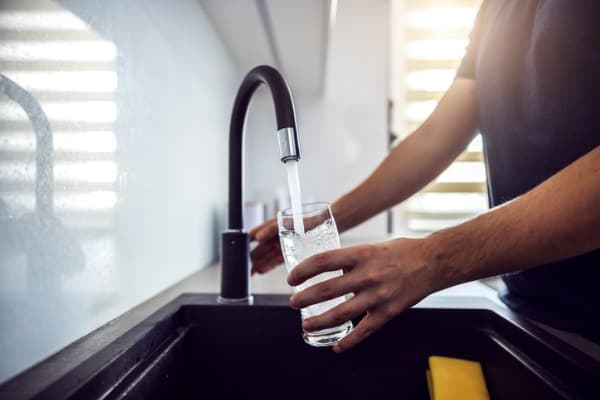 close up of young man pouring fresh water from kitchen sink