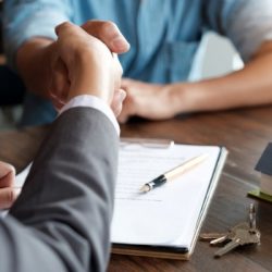 estate agent shaking hands with his customer after contract signature