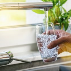 hand holding a glass of water poured from the kitchen faucet