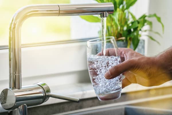 hand holding a glass of water poured from the kitchen faucet