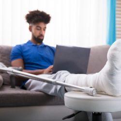 man with broken leg using laptop