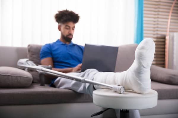 man with broken leg using laptop