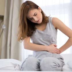 woman sitting on the bed with pain