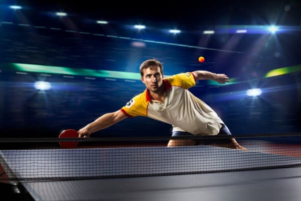 young sports man tennis player playing on black background
