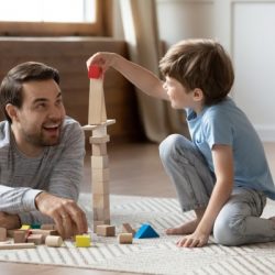 happy father playing with small schoolboy in living room