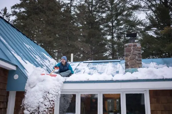 homeowner shovels snow off a roof