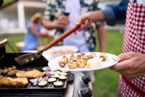 midsection of family outdoors on garden barbecue grilling