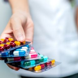 pharmacist or doctor hand holding pack of antibiotic capsule pills