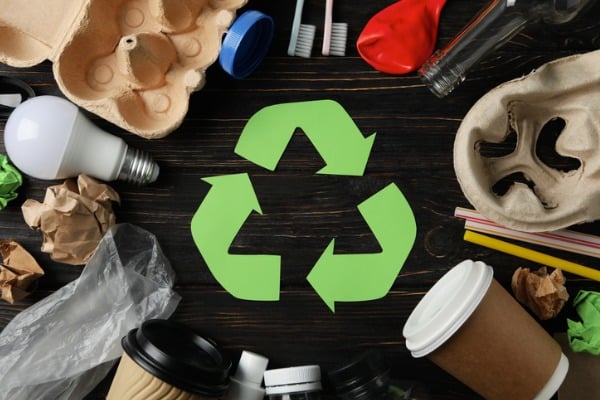 recycle sign on wooden background with different trash