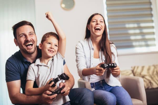 smiling family sitting on the couch together playing video games