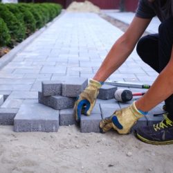 the master in yellow gloves lays paving stones
