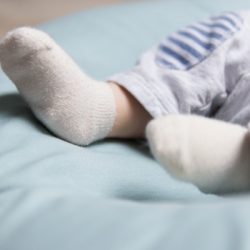 tiny feet of baby lying on soft blue mattress