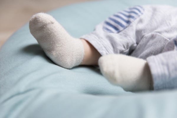 tiny feet of baby lying on soft blue mattress