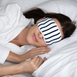 calm serene woman wear sleeping mask resting in comfortable bed