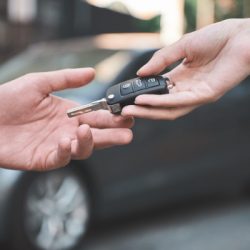 car dealershipyoung man receiving car key from saleswoman