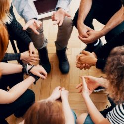closeup of hands of teenagers sitting in a circle during a support