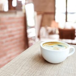 coffee cup on wood table in cafe with blur cafe