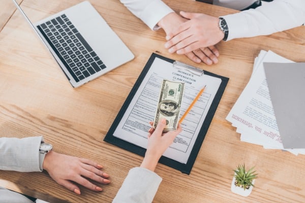 cropped view of businesswoman giving money to worker compensation