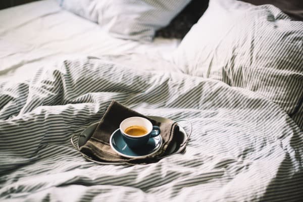delicious fresh morning espresso coffee in bed in a ceramic blue cup