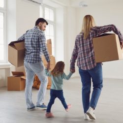 happy family with children moving with boxes in a new apartment house
