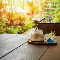 latte ice coffee serve on wooden plate decorated with white flowers