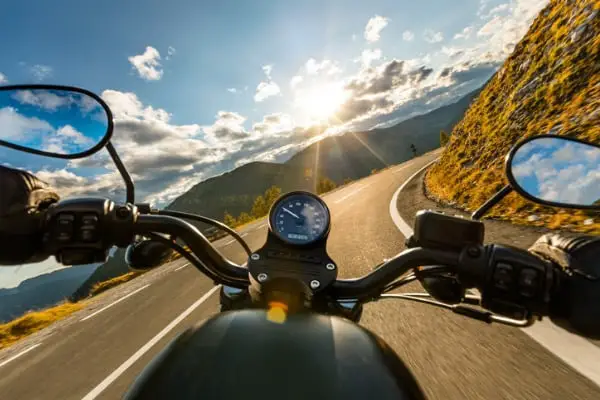 motorcycle driver riding in alpine highway handlebars