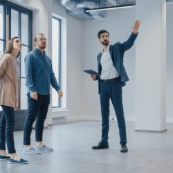 real estate agent showing a new empty office space to young male