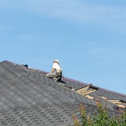 the man on the roof photo of a worker repairing the roof of the house