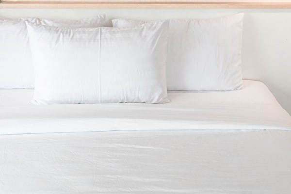 three white pillows neatly arranged on the white bed hotel service