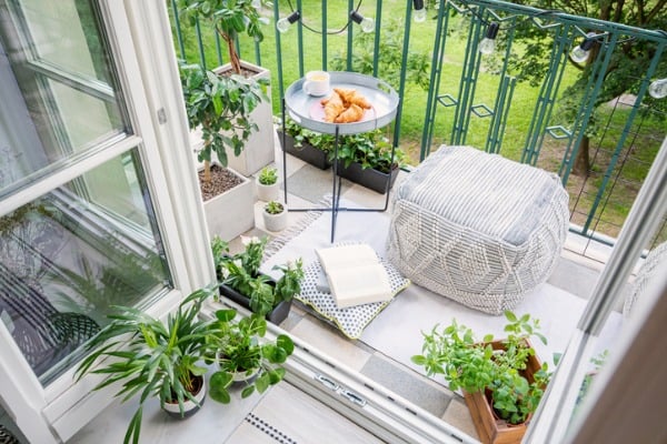 top view of a balcony with plants pouf a table with breakfast