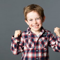 winning young child with tooth missing raising arms for excitement