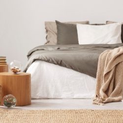 wooden nightstand table next to king size bed with white and grey