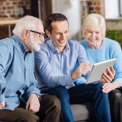 cheerful son teaching his senior parents how to use tablet