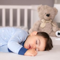 cute little baby boy in light blue pajamas sleeping peacefully on bed