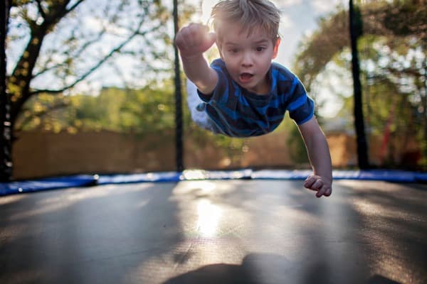 cute little boy jumping on the trampoline like a superhero people