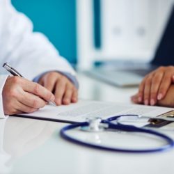 male doctor consults with his patient and writes notes