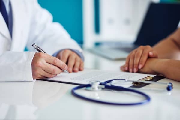 male doctor consults with his patient and writes notes