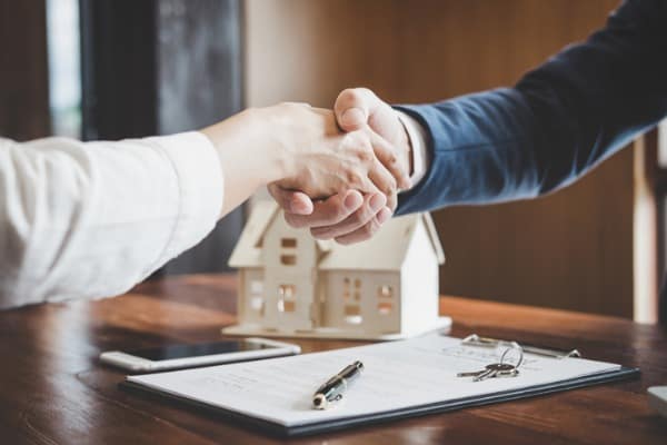 real estate agent and customers shaking hands together celebrating