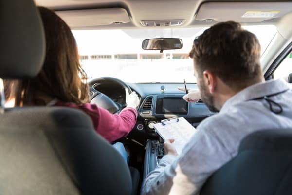 instructor guiding student to drive car